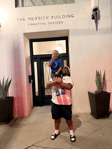 Merrick Brown and his son Maverique smiling together in front of The Merrick Building — Creative Offices in Los Angeles.